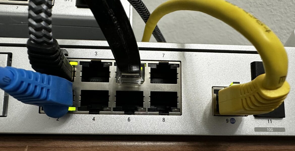 A network switch with blue and yellow Ethernet cables plugged into the ports, showing the port numbers and which cables are in use.